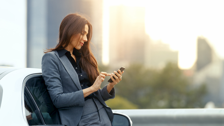 Eine Frau im Hosenanzug, die ihr Smartphone benutzt.