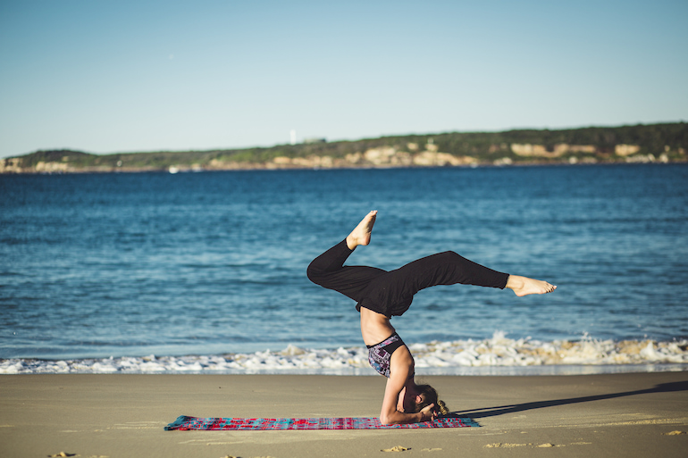 Frau macht Yoga am Strand.