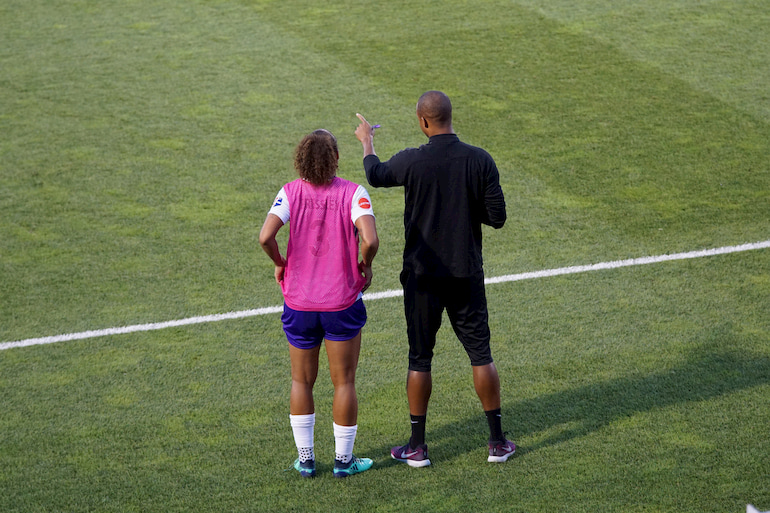 Eine Fußballspielerin steht neben ihrem Coach.