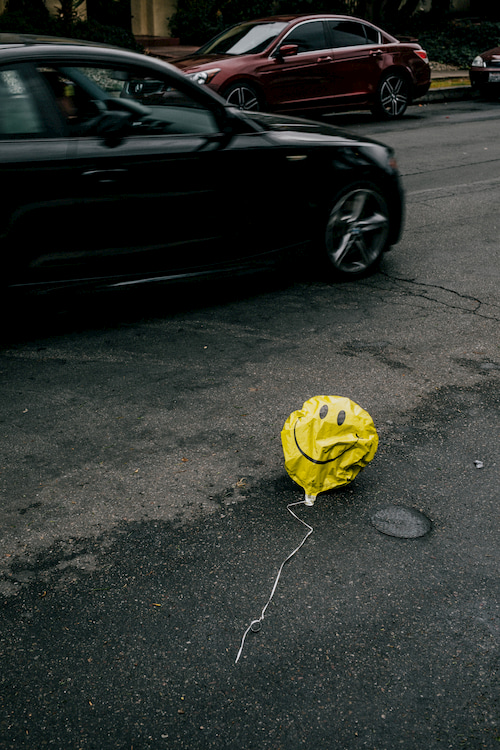 Ein gelber Smiley-Ballon liegt auf dem Boden.
