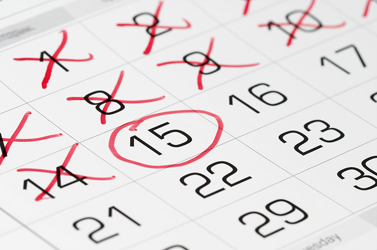 Ein Datum ist auf einem Papier-Kalender mit rotem Stift umkreist, während davorliegende Tage durchkreuzt sind.