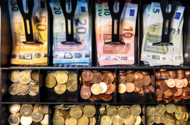 Euro-Banknoten und Euro-Münzen sortiert in einer Kasse.