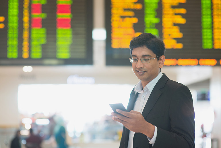 Ein Mann schaut am Flughafen auf sein Smartphone.
