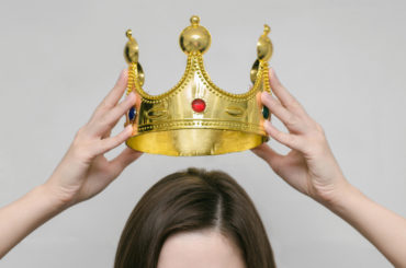 Person setzt sich eine Krone auf.