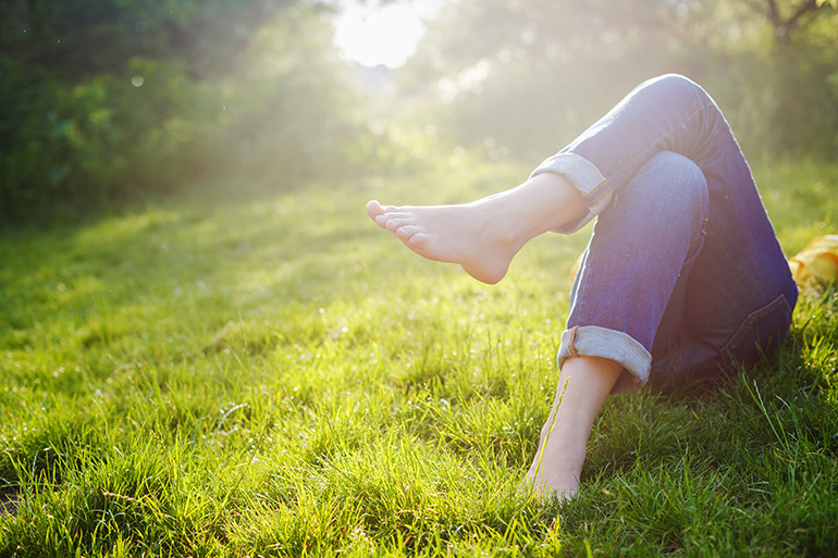 Eine Frau liegt in ihrem Sabbatical im grünen Gras und entspannt.