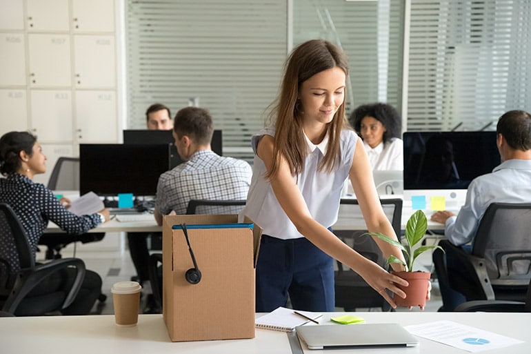 Probezeit geschafft: Eine Frau entpackt ihren Karton für neuen Job im Büro.