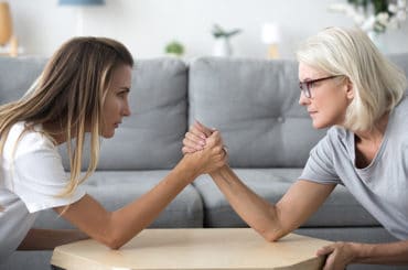 Eine junge und eine alte Frau duellieren sich beim Armdrücken.