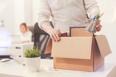 Ein Mann packt nach der Kündigung im Büro seine Sachen zusammen.