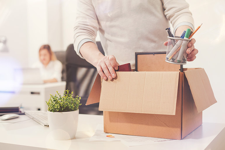 Ein Mann packt nach der Kündigung im Büro seine Sachen zusammen.