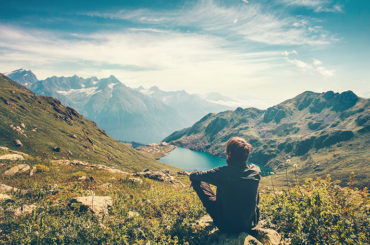 Ein Mann sitzt in den Bergen an einem See und genießt das Sabbatical.