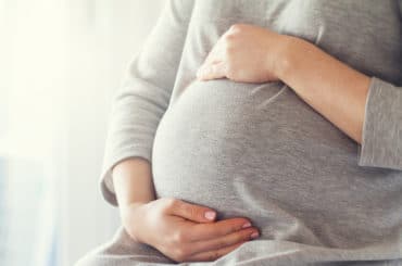 Eine schwangere Frau hält liebevoll ihren Bauch.