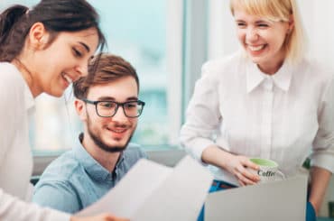 Drei Arbeitskollegen lachen gemeinsam.