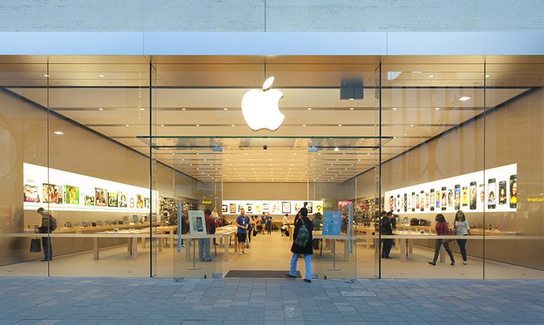 Frontalaufnahme eines Apple Stores, in dem Menschen einkaufen.