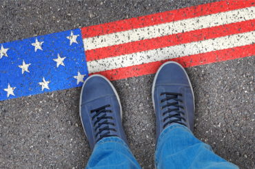 Eine Person steht vor der amerikanischen Flagge, die auf den Boden gemalt ist.
