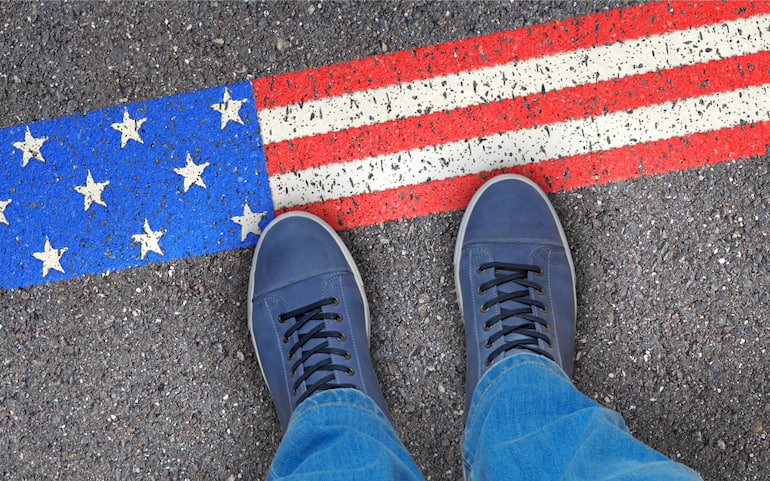 Eine Person steht vor der amerikanischen Flagge, die auf den Boden gemalt ist.
