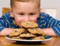 Ein willensstarkes Kind sitzt vor einem Teller mit Keksen
