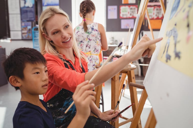 Berufsalltag einer Erzieherin: Eine junge Kunstlehrerin unterrichtet einen Schüler.
