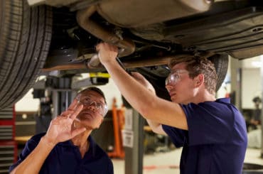 Auszubildender bekommt Tipps zur Reparatur eines Auspuffs während der Ausbildung