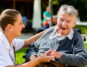 Altenpflegerin kümmert sich um alte Frau im Rollstuhl