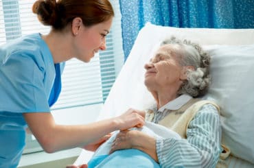 Eine Pflegehelferin kümmert sich um eine Patientin