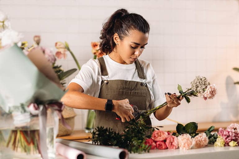 Eine Floristin bindet einen Blumenstrauß und beschneidet dafür die Blumen