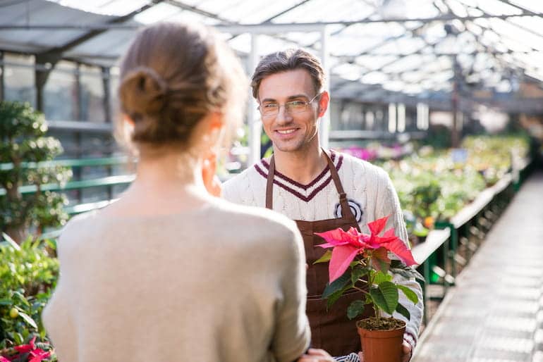 Ein Florist berät eine Kundin im Gewächshaus