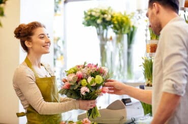 Eine Floristin verkauft einem Kunden einen Blumenstrauß