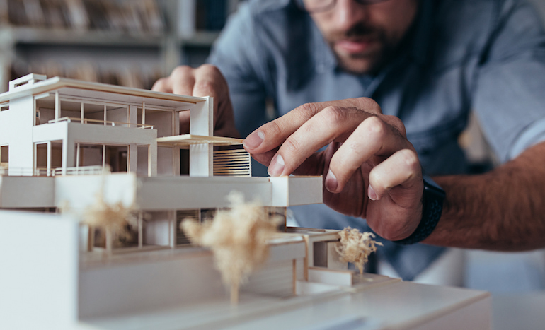 Architekt setzt Modell eines Gebäudes zusammen