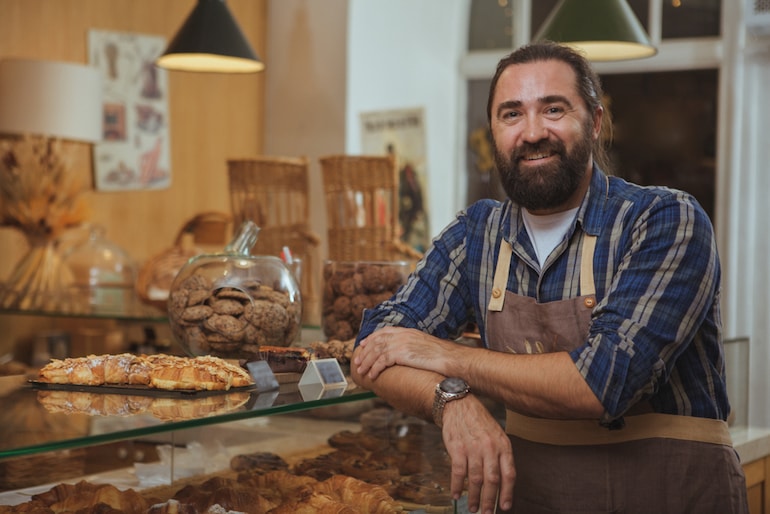 Bäcker steht vor der Ladentheke seiner Bäckerei