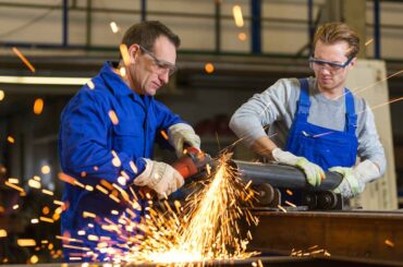 Zwei Metallbauern fertigen ein Metallbauteil und schleifen dieses