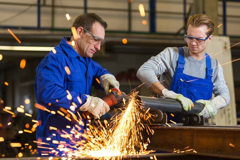 Zwei Metallbauern fertigen ein Metallbauteil und schleifen dieses