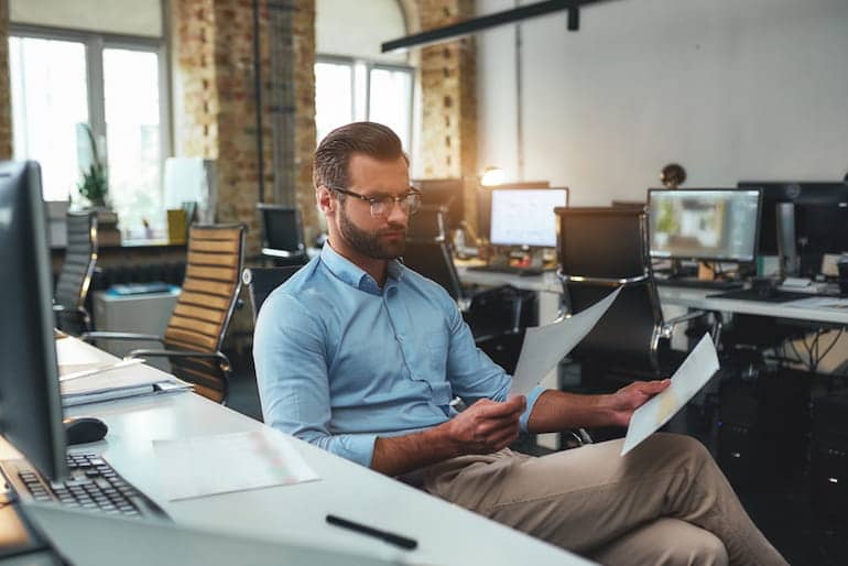 Ein Chefredakteur sitzt im Büro und überprüft die Texte der Redakteure