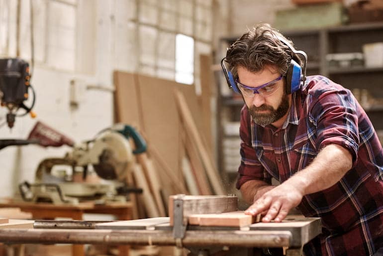 Ein Tischler schneidet in seiner Werkstatt Holz zu