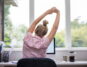 Eine Frau sitzt vor dem Computer und macht Rückenübungen am Arbeitsplatz