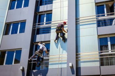 Zwei Gebäudereiniger reinigen die Fassade eines Gebäudes