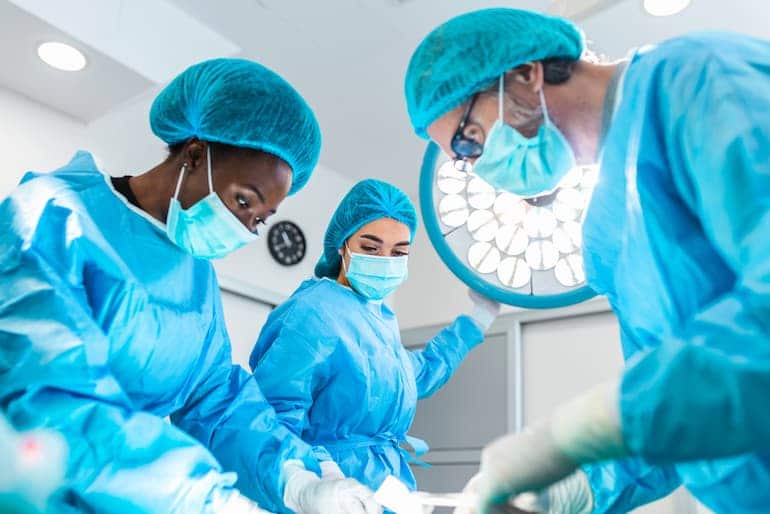 Drei Chirurg*innen operieren einen Patienten im OP-Saal