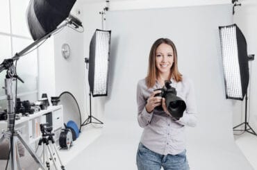 Eine Fotografin steht in ihrem Fotostudio und lächelt