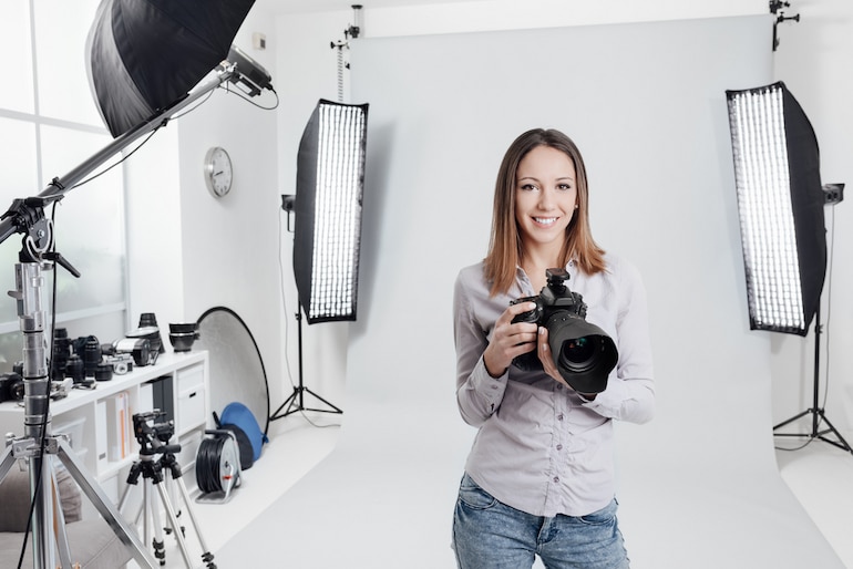 Eine Fotografin steht in ihrem Fotostudio und lächelt